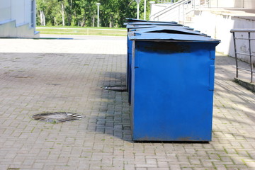 Metal garbage containers are arranged in a row.