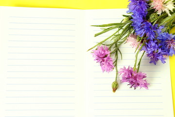 blank notepad with flower on a yellow background top view