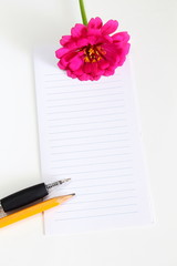 Naklejka premium blank notepad with flower,pencil,pen on a white background top view