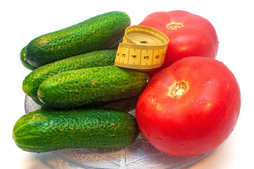 Cucumbers with tomatoes and measuring tape in a plate