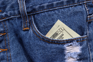 Banknote money twenty US dollar in the pocket of blue jeans.