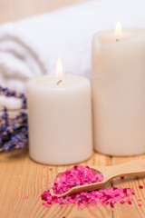 Obraz na płótnie Canvas close up sea salt in wooden spoon and burning candles soothing spa treatments with lavender
