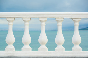 classic white balustrade with stone columns on blue sky and black sea water background, stock photo image