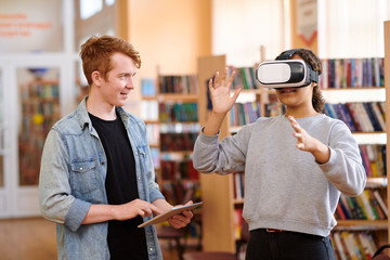 Mixed-race student with vr headset and her classmate with touchpad
