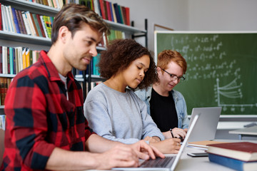 Three contemporary college students working individually