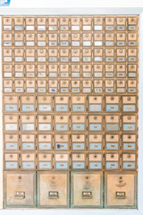 Rows of mid-century modern design post office mailboxes in brass metal.