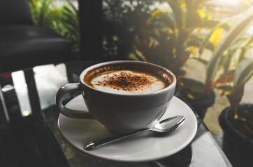 close up modern hot black coffee the cappuccino on dark background with coffee bubble foam pattern and texture in white cup looking and feel so delicious on glasses table in coffee shop.