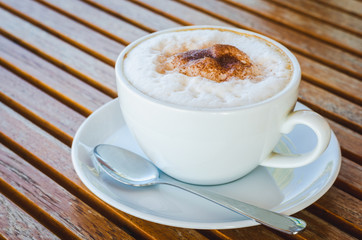 close up modern hot black coffee the cappuccino on wood background with coffee bubble foam pattern and texture in white cup looking and feel so delicious on glasses table in coffee shop.
