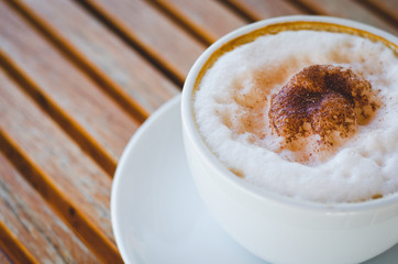 close up modern hot black coffee the cappuccino on wood background with coffee bubble foam pattern and texture in white cup looking and feel so delicious on glasses table in coffee shop.