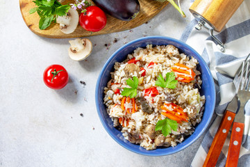 Diet menu. Healthy food. Vegetarian vegetable mushrooms pilaf. Rice with eggplant and mushrooms on stone table. Top view flat lay. Free space for your text.