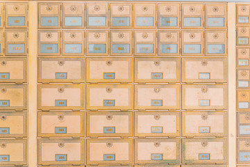 Rows of mid-century modern design post office mailboxes in brass metal.