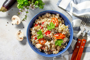 Fototapeta na wymiar Diet menu. Healthy food. Vegetarian vegetable mushrooms pilaf. Rice with eggplant and mushrooms on stone table. Top view flat lay.