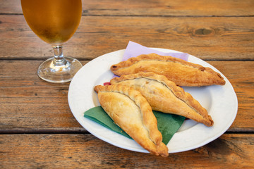 Kibinai with cold beer, traditional Lithuanian food, pastries filled with various meat, onion and pepper, popular with Karaite ethnic minority in Trakai, Lithuania, wooden table