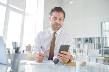 Young businessman scrolling in smartphone