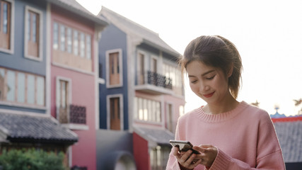 Cheerful Asian backpacker blogger woman using smartphone for direction and looking on location map while traveling at Chinatown in Beijing, China. Lifestyle backpack tourist travel holiday concept.