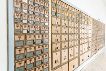 Rows of mid-century modern design post office mailboxes in brass metal.