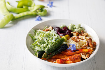 Buddha bowl with roast beetroots, carrots, zucchini and green peas salad