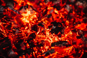 Orange flames and red hot coals in the fireplace in the gazebo in the garden