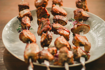 Delicious fried pork kebab strung on skewers on the table in the gazebo
