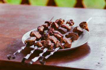 Delicious fried pork kebab strung on skewers on the table in the gazebo