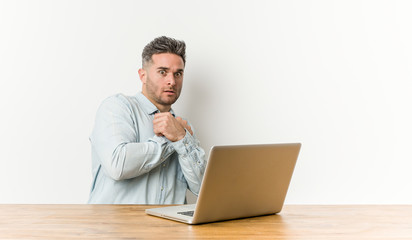 Young handsome man working with his laptop scared and afraid.
