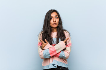 Young fashion indian woman points sideways, is trying to choose between two options.