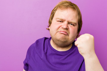 Obraz premium Young authentic redhead fat man showing fist to camera, aggressive facial expression.