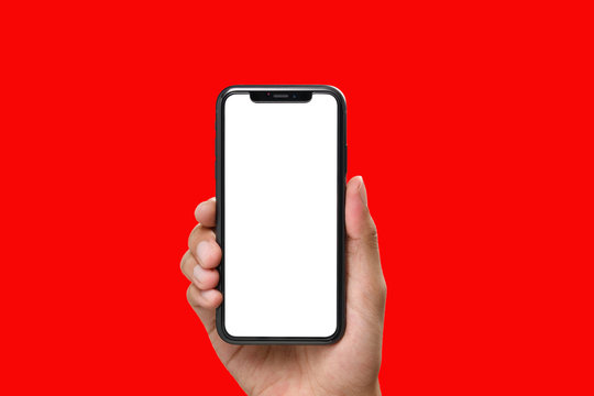 Hand holding the black smartphone with blank screen and modern frame less design on red colour background