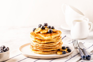 Pancakes with banana,  blueberries on white plate.