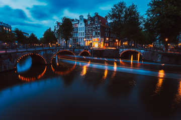 Bridge illumination and boat light trails in evening Amsterdam with reflection in Herengracht...