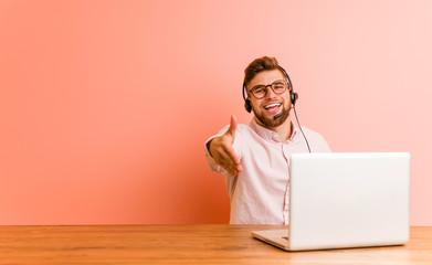 Young man working in a call center stretching hand at camera in greeting gesture.