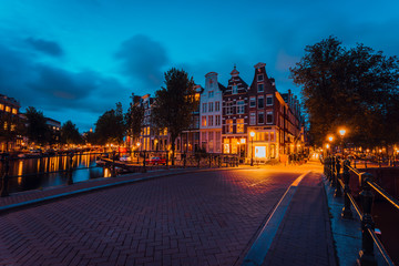 Amsterdam illuminated bridge with typical dutch houses in evening blue hour lights, Holland, Netherlands