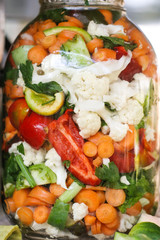 Hand made rural pickled vegetables food for the winter with carrots, peppers, paprika, cauliflower and celery in a big jar.