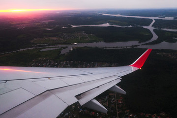 The river and susnet or sunrise under the wing of the plane during the landing. View through the illuminator