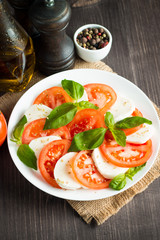 Close-up photo of caprese salad with ripe tomatoes, basil, buffalo mozzarella cheese. Italian and Mediterranean food concept. Fresh and healthy organic meal. Starter and antipasti.