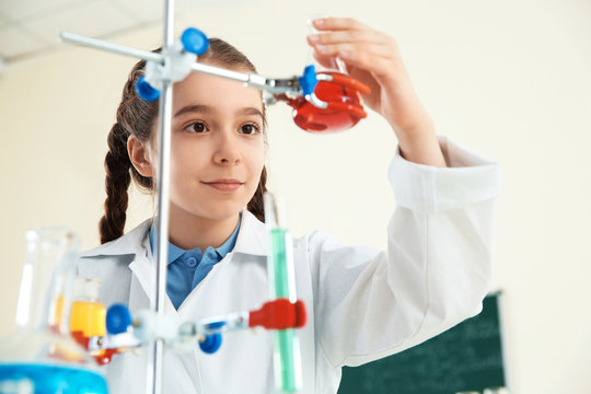 Smart pupil looking at flask with reagent on holder in chemistry class