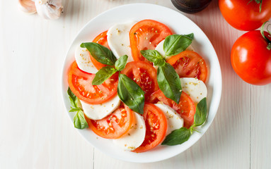 Close-up photo of caprese salad with ripe tomatoes, basil, buffalo mozzarella cheese. Italian and Mediterranean food concept. Fresh and healthy organic meal. Starter and antipasti.