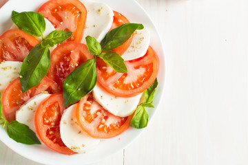 Close-up photo of caprese salad with ripe tomatoes, basil, buffalo mozzarella cheese. Italian and Mediterranean food concept. Fresh and healthy organic meal. Starter and antipasti.