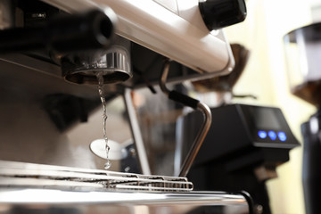 Water pouring from modern coffee machine, closeup. Space for text