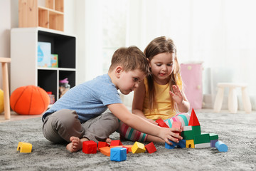 Little children playing with colorful blocks indoors