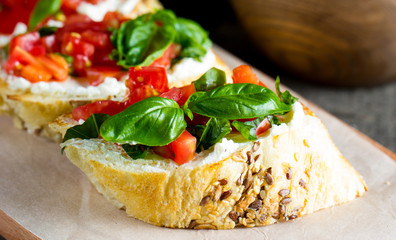 Tomato and cheese fresh made bruschetta. Italian tapas, antipasti with vegetables, herbs and oil on grilled ciabatta and baguette bread.