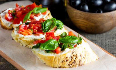Tomato and cheese fresh made bruschetta. Italian tapas, antipasti with vegetables, herbs and oil on grilled ciabatta and baguette bread.
