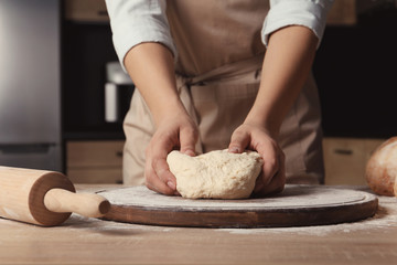 Female baker preparing bread dough at table, closeup