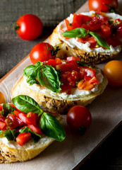 Tomato and cheese fresh made bruschetta. Italian tapas, antipasti with vegetables, herbs and oil on grilled ciabatta and baguette bread.