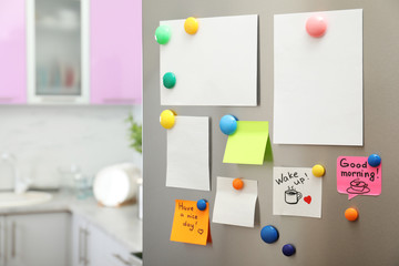 Many notes and empty sheets with magnets on refrigerator door in kitchen. Space for text