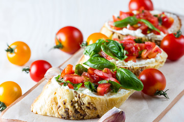 Tomato and cheese fresh made bruschetta. Italian tapas, antipasti with vegetables, herbs and oil on grilled ciabatta and baguette bread.