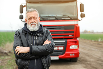 Portrait of mature driver at modern truck outdoors