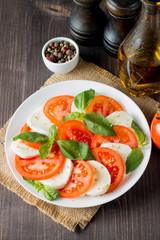 Close-up photo of caprese salad with ripe tomatoes, basil, buffalo mozzarella cheese. Italian and Mediterranean food concept. Fresh and healthy organic meal. Starter and antipasti.