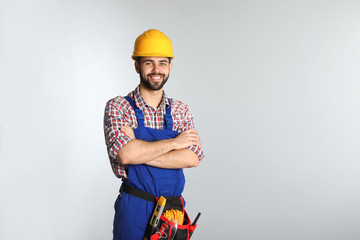 Portrait of construction worker with tool belt on light background. Space for text - obrazy, fototapety, plakaty