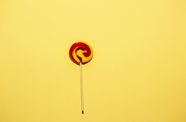 Red, yellow color lollipops on yellow paper background. Concept of hollyday card